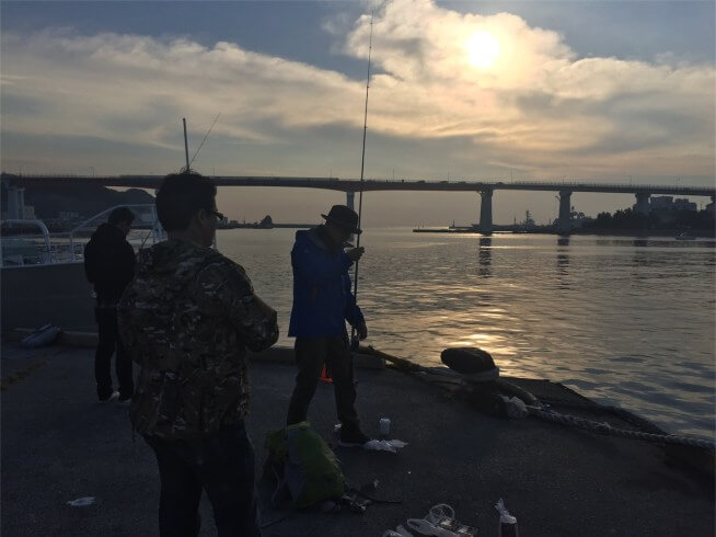 花暮岸壁の朝日と釣り人